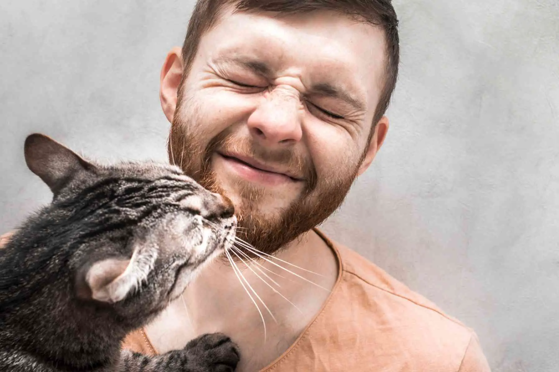Cat rub its gums on young man's face