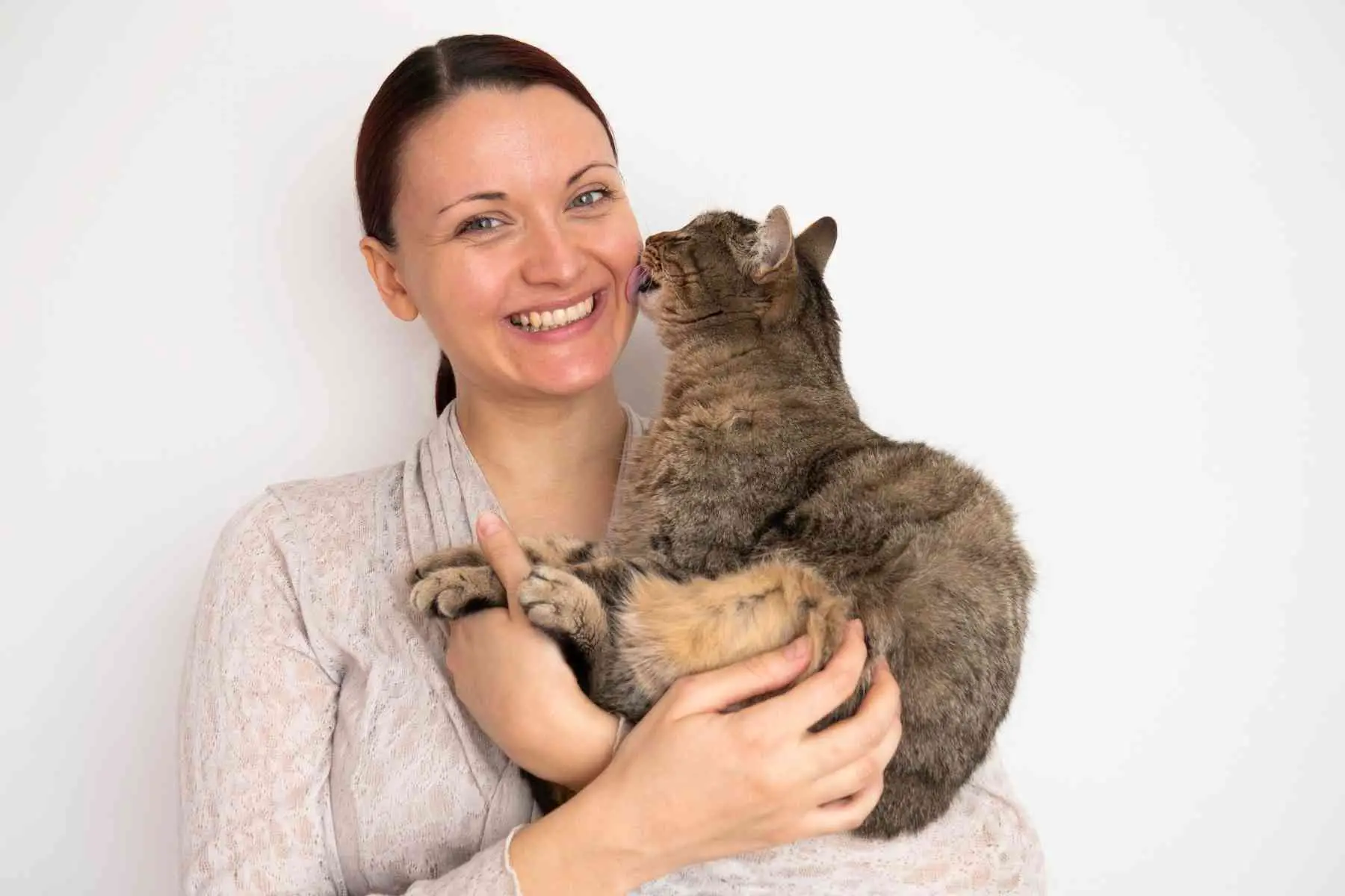 Cat licking smiling woman's face