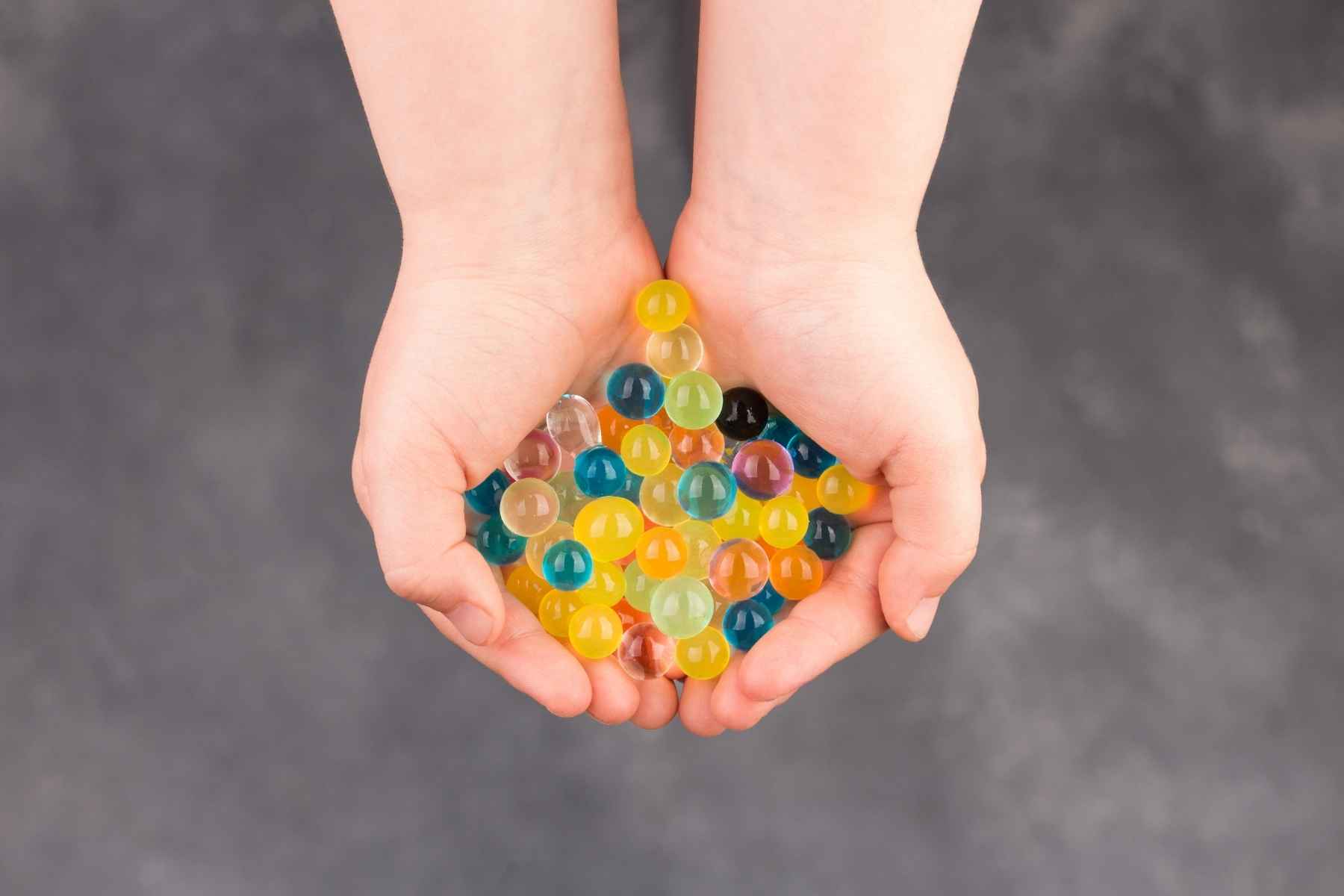 Kid holding orbeez in many colors in his hands