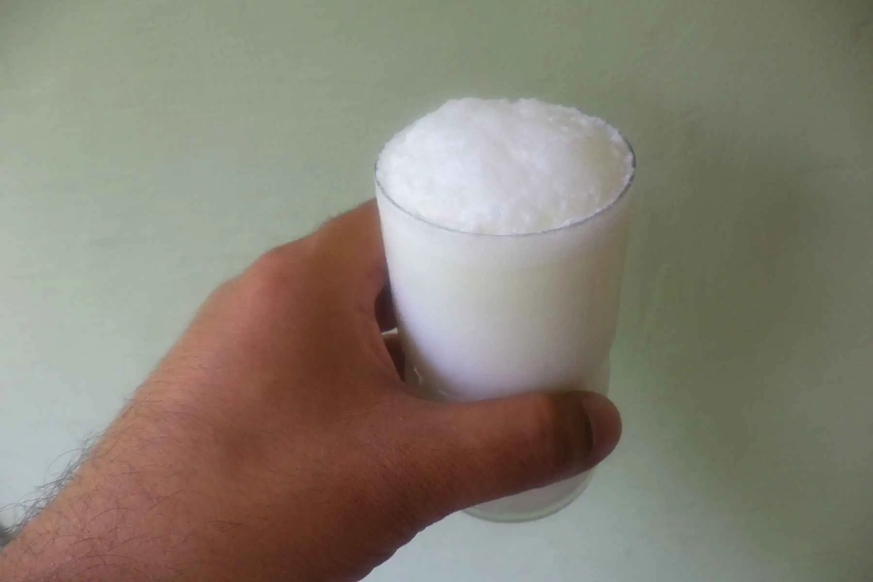 Hand holding a glass of buttermilk